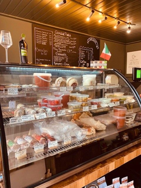 De toonbank met een gekoelde vitrine vol antipasti en het krijtbord met focaccia, broodjes to go en gevulde pasta