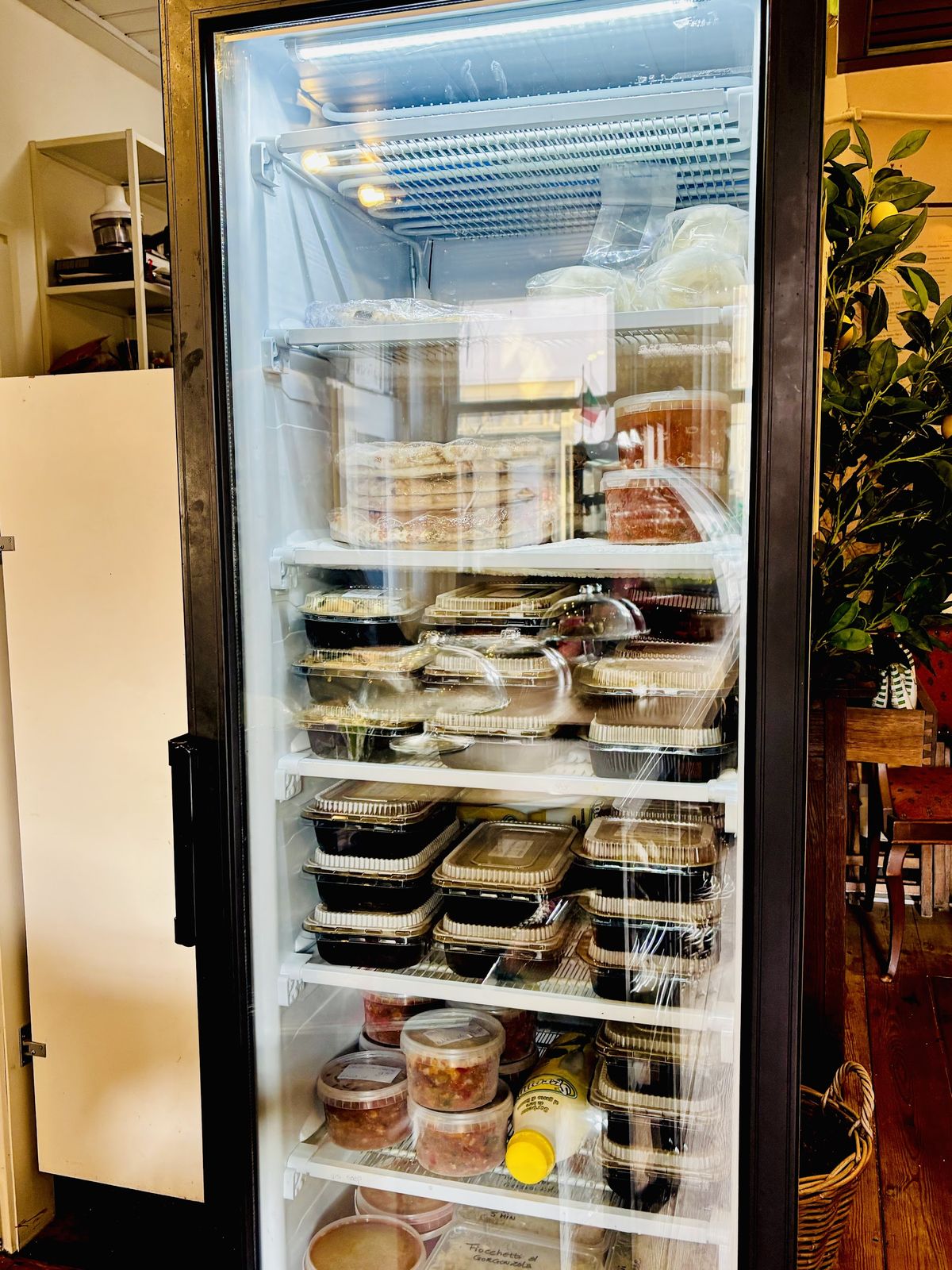 De koelkast met glazen deur, gevuld met huisgemaakte maaltijden in bakjes