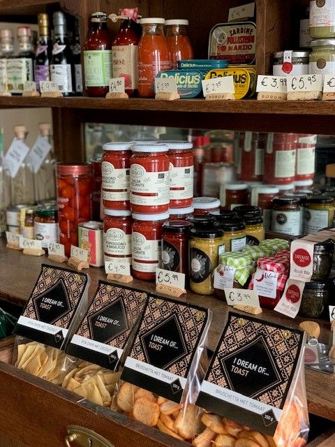 Schappen met tomatensaus, antipasti in potten, sardines in blik en doosjes crostini